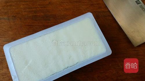 首先来切豆腐丝,打开盒装豆腐,用刀托着倒扣在菜板上。